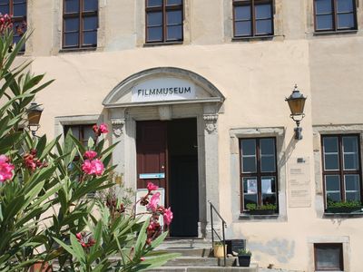 Das Bild zeigt den Eingang des Filmmuseums in Ballenstedt. Im Vordergrund blüht Oleander. 